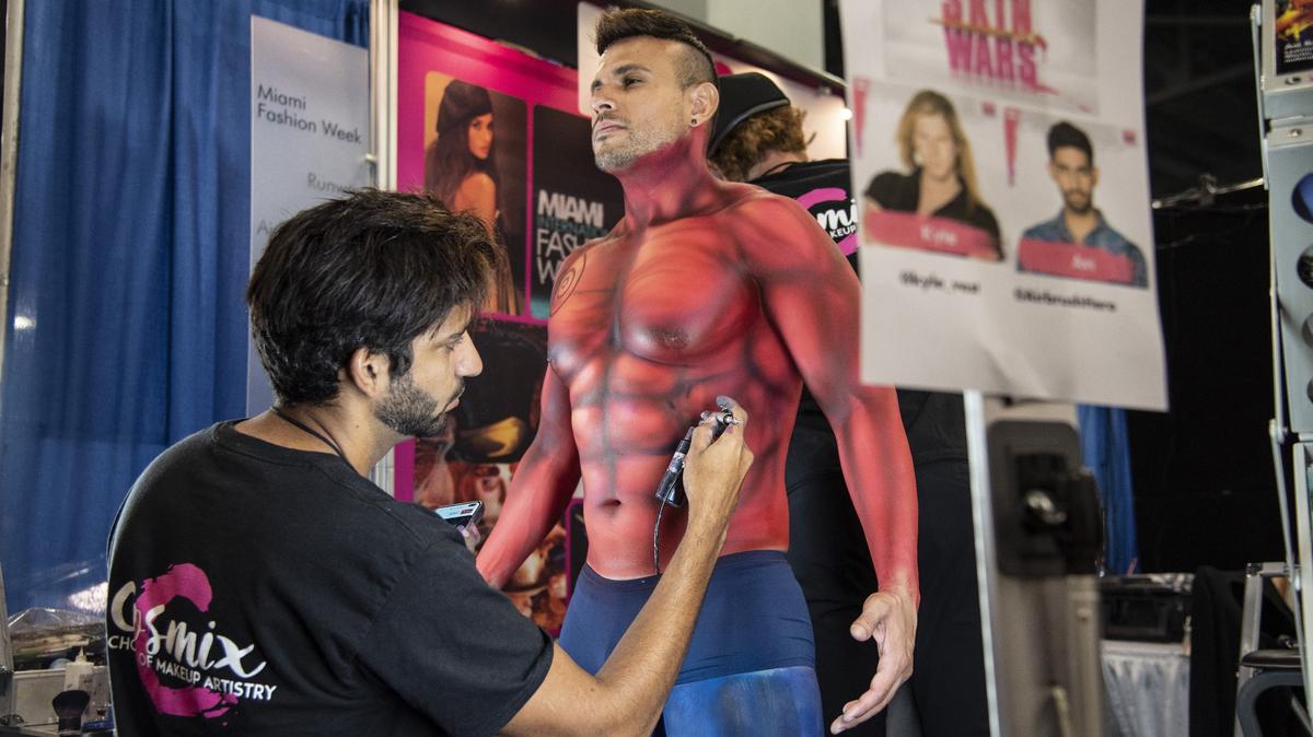 Avi Ram (derecha) pinta a C.A. López, de 39 años, como Hellboy durante la Florida Supercon en el Centro de Convenciones de Miami Beach el 5 de julio de 2019.