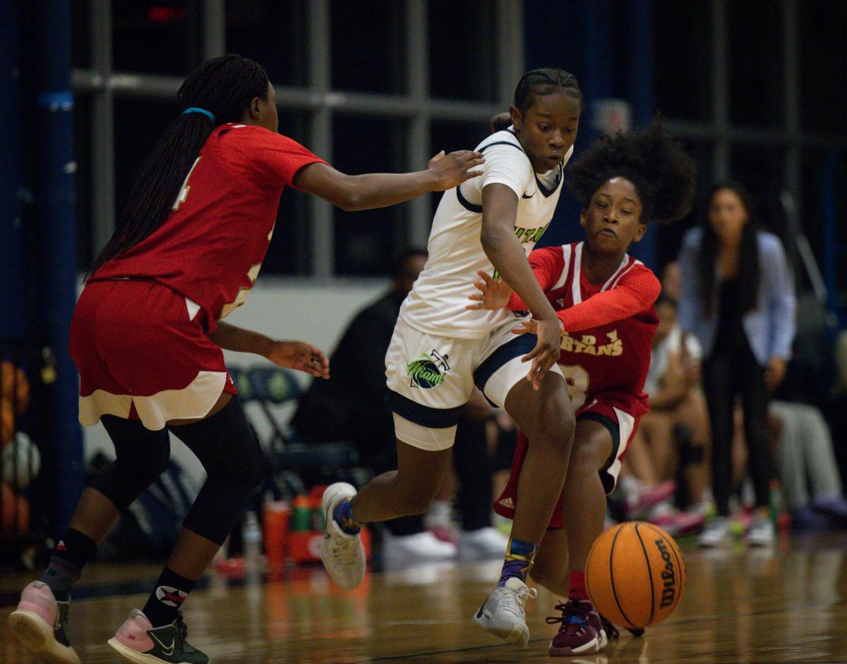 SLAM’s Jim’Miyah Branton (12) bounces the ball over the arms of Monsignor Pace’s Aleaijah Russell (3) and around Catherine Guillaume (24) during the first quarter of the girls basketball regional semifinal on Monday, Feb. 19, 2024, at SLAM Miami.