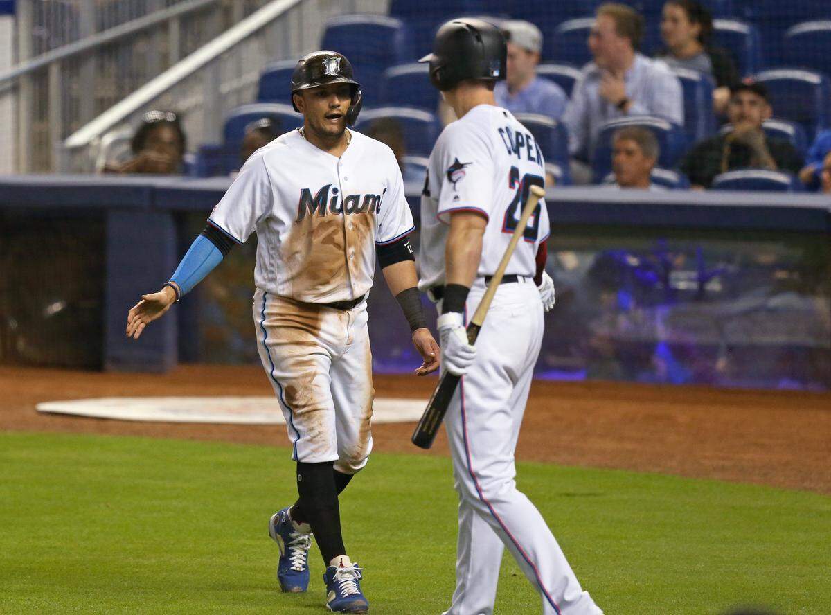 Miami Marlins shortstop Miguel Rojas (19) is congratulated by right fielder Garrett Cooper (26) after scoring during the third inning of an Major League Baseball game against the Washington Nationals at Marlins Park in Miami on Thursday, June 27, 2019.