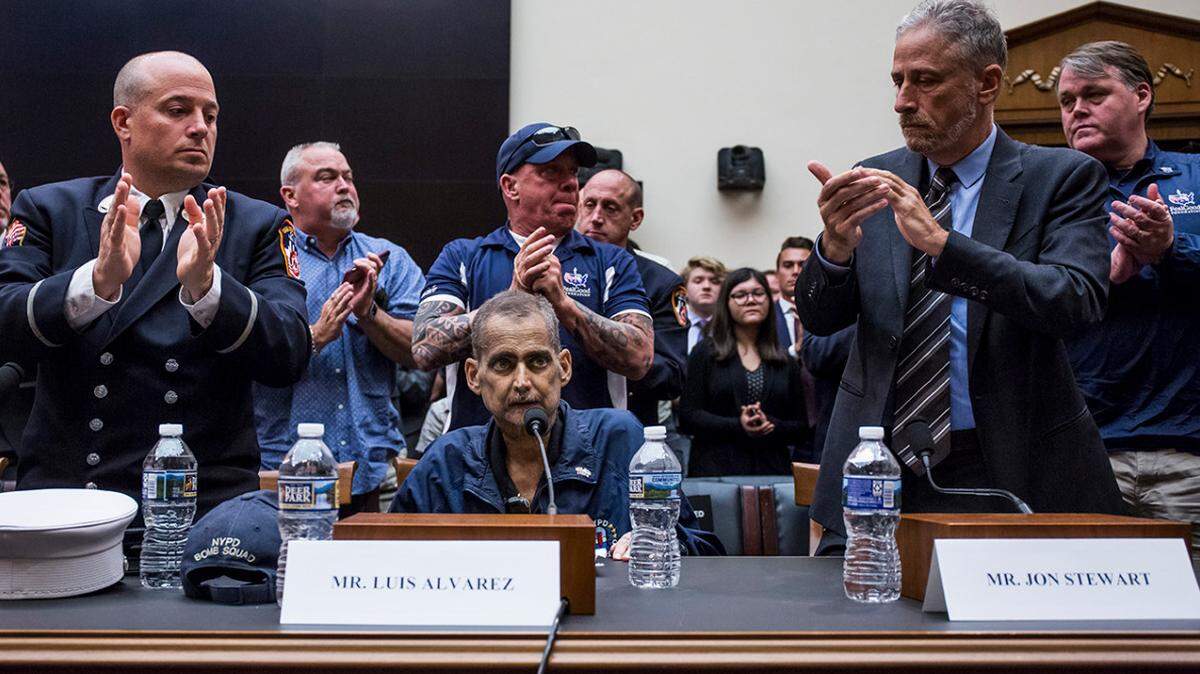 Jon Stewart, right, and others applaud Luis Alvarez after his testimony before the House Judiciary Committee on reauthorizing the September 11th Victim Compensation Fund. Alvarez,  a retired New York police detective and 9/11 responder died soon after. 