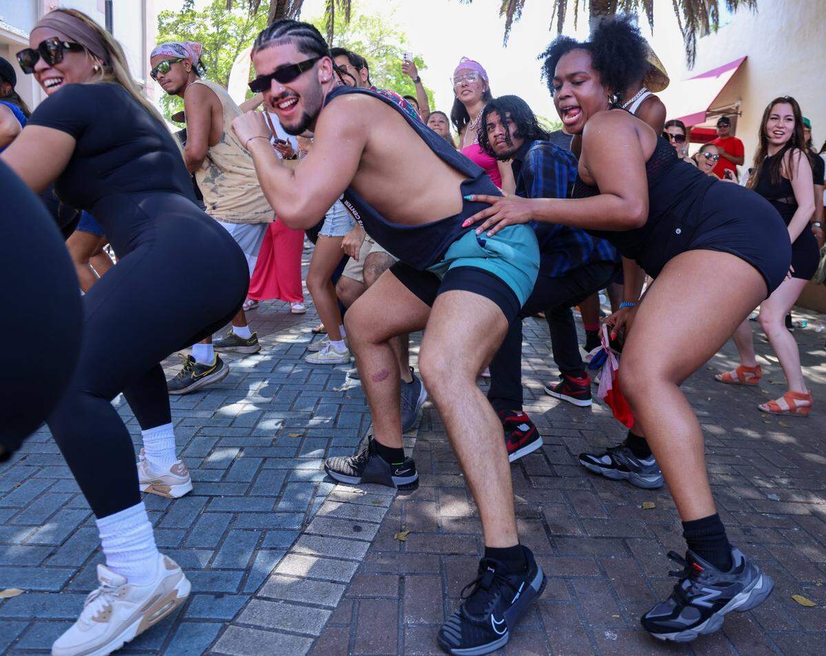 Festival goers Steven Bartumeu, center, and Desyree Hernandez, right, get the Latin vibe going at the small music stage on 700 block of SW 15th Avenue.