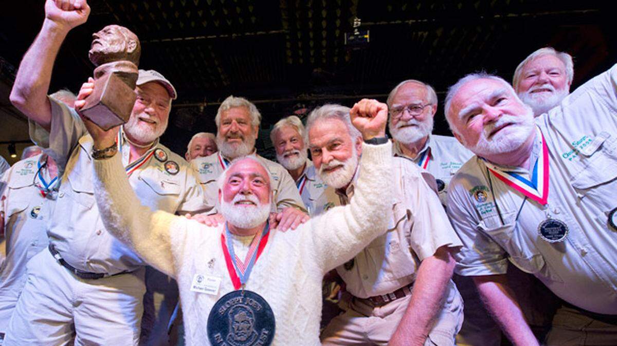 Michael Groover, kneeling, husband of celebrity chef Paula Deen, poses with past winners of the Hemingway Look-Alike Contest Saturday, July 21, 2018, at Sloppy Joe’s Bar in Key West.