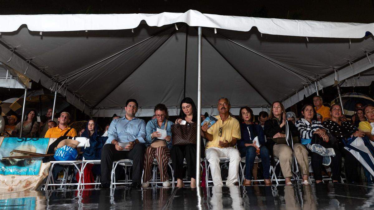 Congregants worship in the rain outside Ermita de la Caridad during the annual celebration of the feast day of Cuba's patroness, Our Lady of Charity, at the National Shrine of Our Lady of Charity, on Monday, September 8, 2025, in Coconut Grove, Fla.