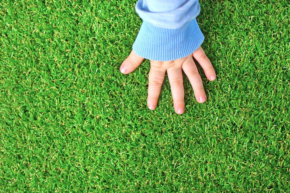 baby touches artificial grass with hand