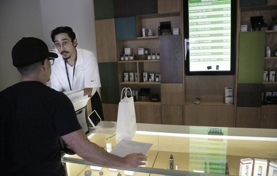 Patient consultant Andy Luis shows the medical marijuana merchandise to a customer at Trulieve, 4020 NW 26th St.  in Miami.