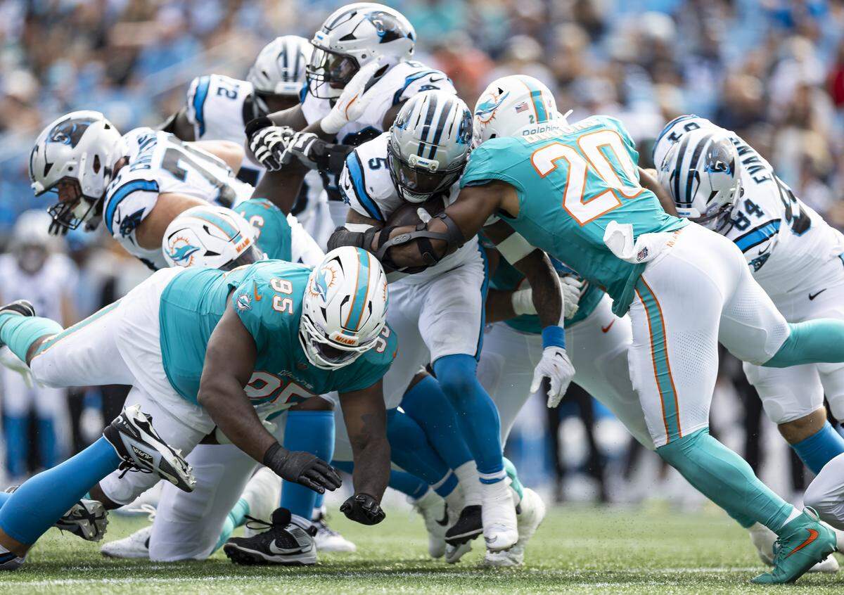 Miami Dolphins linebacker Jordyn Brooks (20) and defensive tackle Benito Jones (95) work to tackle Carolina Panthers running back Rico Dowdle (5) in the second half of their NFL game at the Bank of America Stadium on Sunday, Oct. 5, 2025, in Charlotte, N.C.