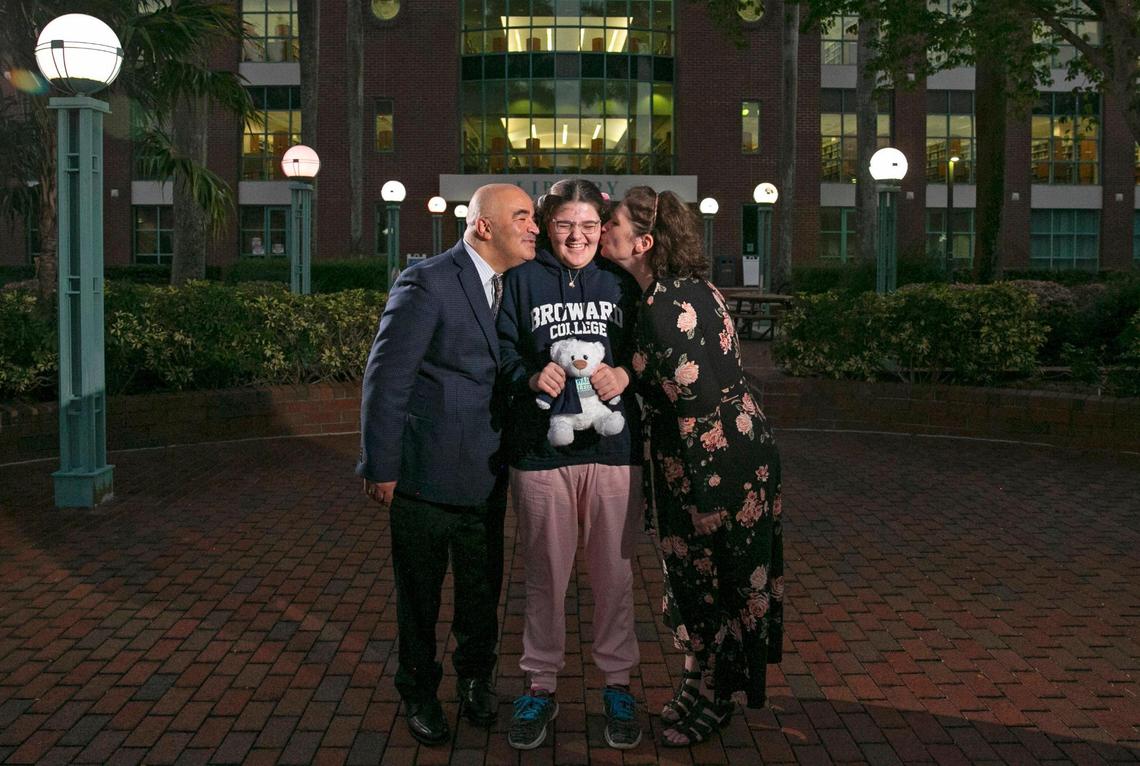 Sawsan Ahmed, laughs as her proud parents, Wesam Ahmed and Jeena Santos Ahmed lean in to kiss her outside of the Broward College library building, Dec. 13, 2021.