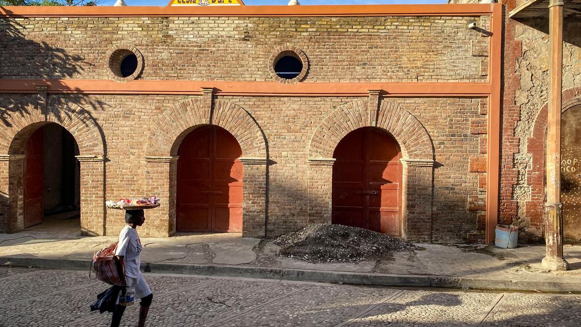A woman walks by a building undergoing repairs in Jacmel where the tourism industry has taken a hit because of gang violence.