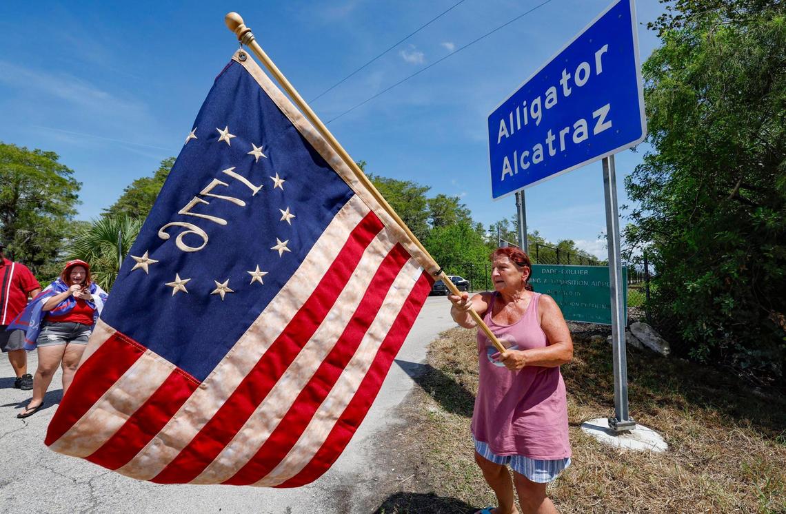 Rena Mourer, una partidaria de Alligator Alcatraz, ondea una bandera estadounidense Betsy Ross 1776 en la entrada principal de Alligator Alcatraz, mientras legisladores de Florida y miembros del Congreso recorren la cárcel de inmigrantes ubicada en los Everglades, a 36 millas al oeste del distrito comercial central de Miami, en el Condado Collier, Florida, el sábado 12 de julio de 2025.