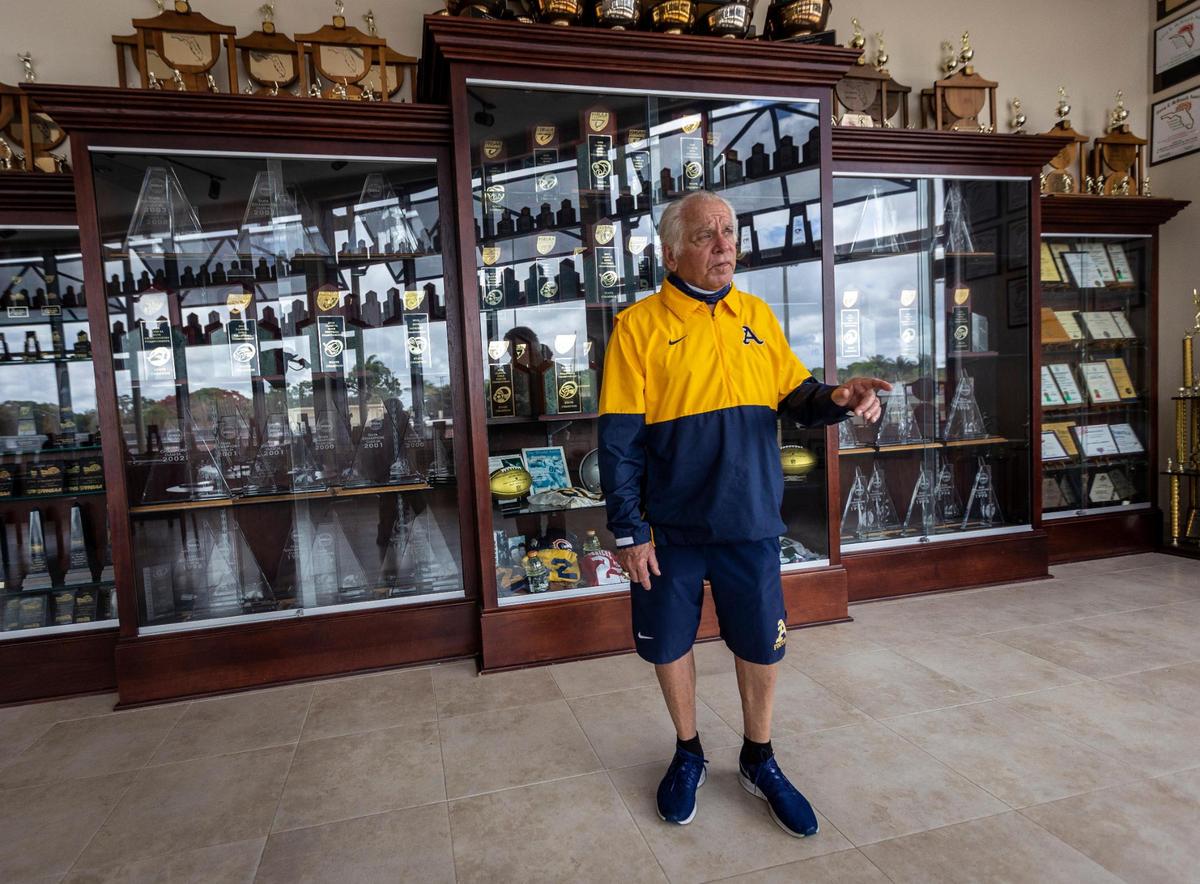 Fort Lauderdale, Florida, June 2, 2021 -Surrounded by trophies won by St. Thomas Aquinas sports teams, George Smith, Athletic Director at St. Thomas Aquinas High School in Fort Lauderdale gestures as he talks to a Miami Herald reporter during an interview. George Smith, one of the most storied coaches in high school football history, is retiring at the end of the school year.