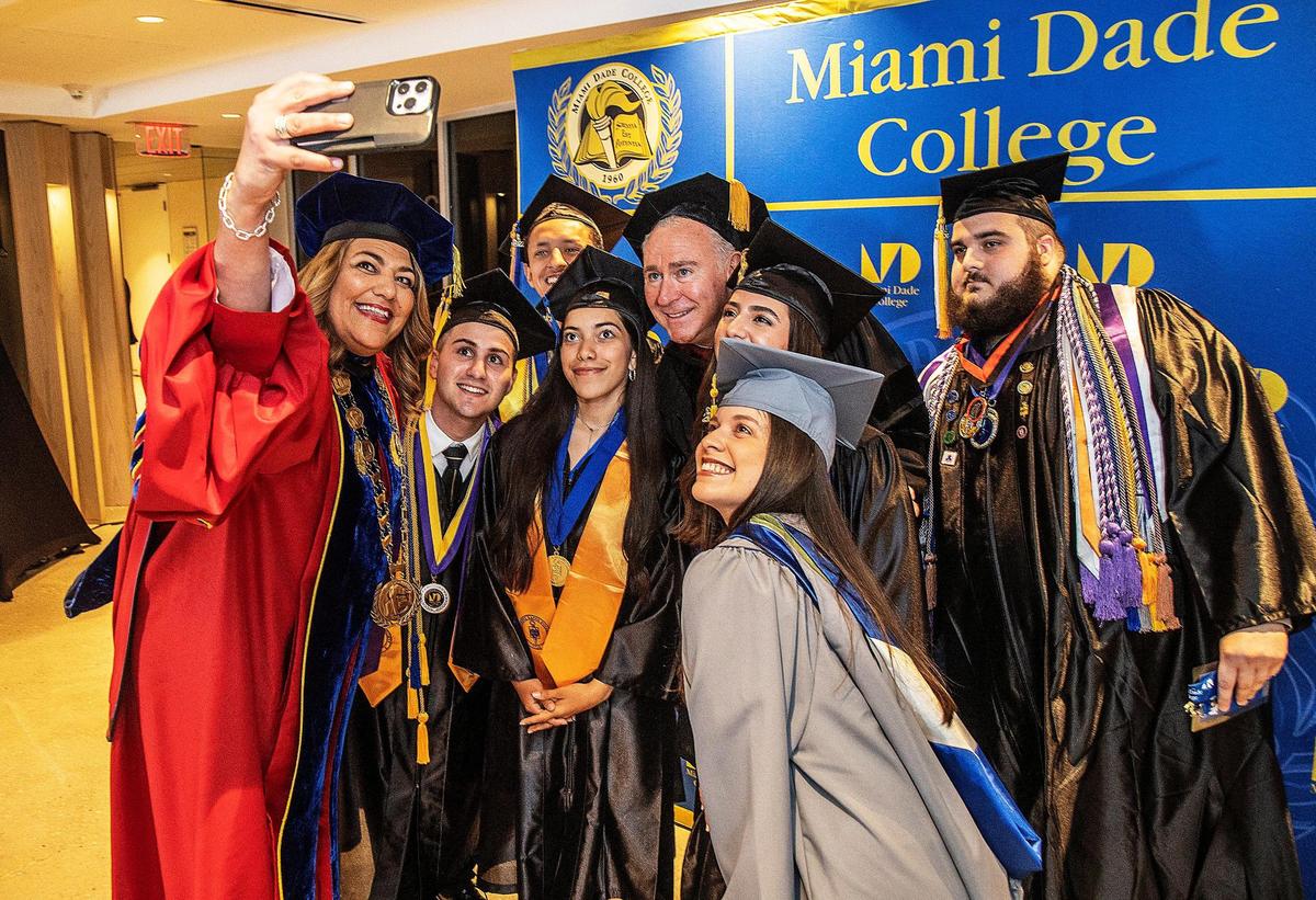 La presidenta de Miami Dade College (MDC), Madeline Pumariega, tomándose un selfie con el fundador y presidente ejecutivo de Citadel, Ken Griffin, y un grupo de estudiantes de Honors College durante la ceremonia de graduación en loanDepot Park, el sábado 22 de abril de 2023.
