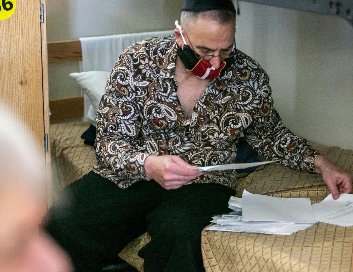 Heriberto Delvalle looks through papers at his bunk at Camillus House in Miami.