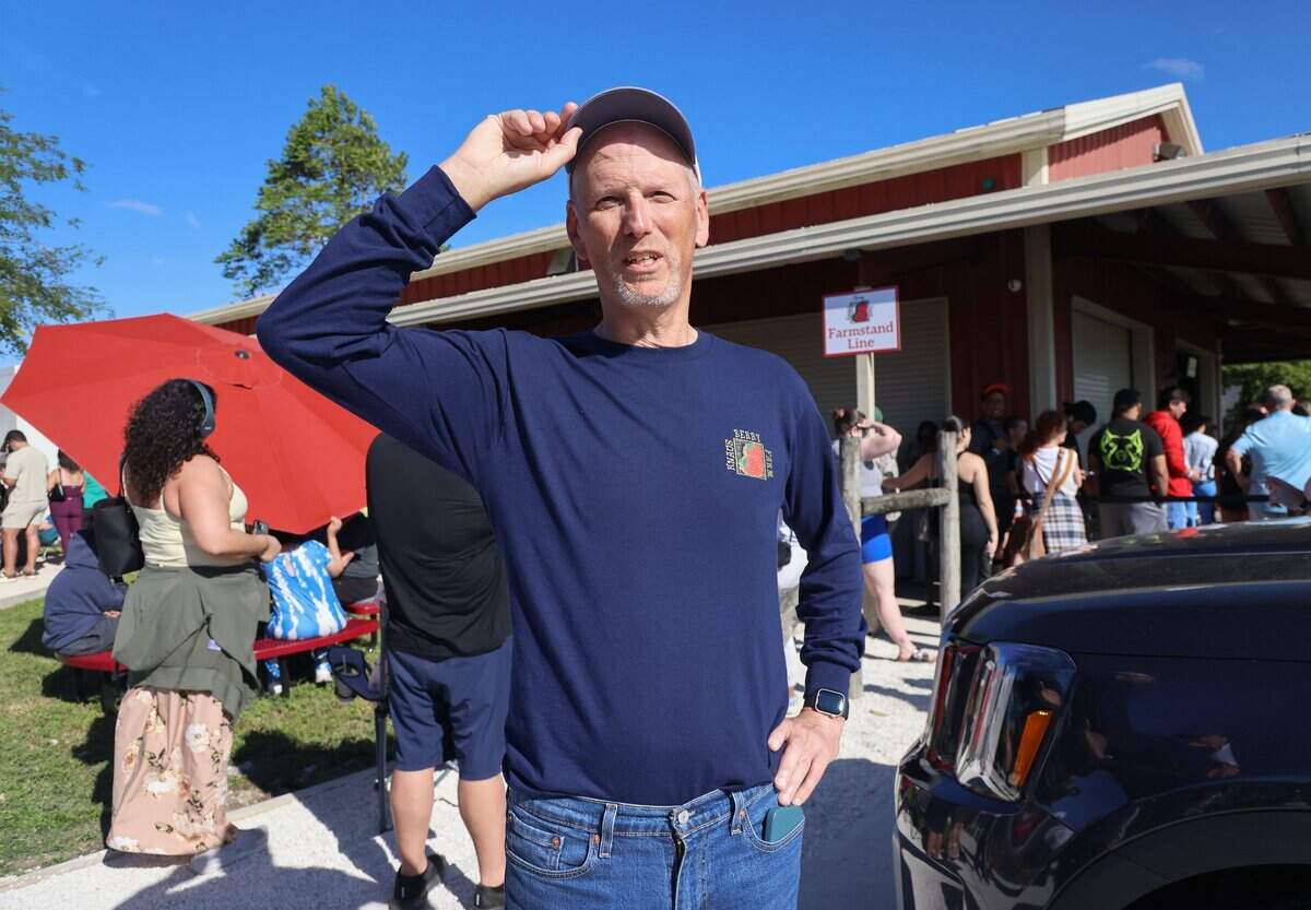 Knaus Berry Farm general manager Joel White adjusts his hate in front of a winding line of patrons in the Redlands, near Homestead, Fla., on Monday, December 22, 2025. He enjoys seeing visitors in awe when they see Miami has miles and miles of farmland.