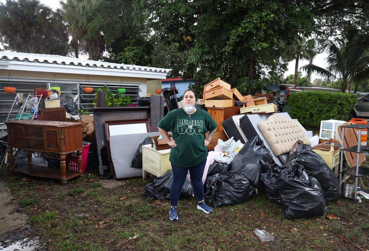 Edgewood resident Tara Hardy, 34, takes a break from cleaning she stands outside her front lawn where most of the contents of her home were discarded due to water damage. On Monday, April 17, 2023, less than a week after unrelenting rainfall flooded the streets of the Edgewood neighborhood in Fort Lauderdale, residents continued to clean out their soaked homes. Many worked hard in hopes they’ll be able to salvage their homes and move back in.