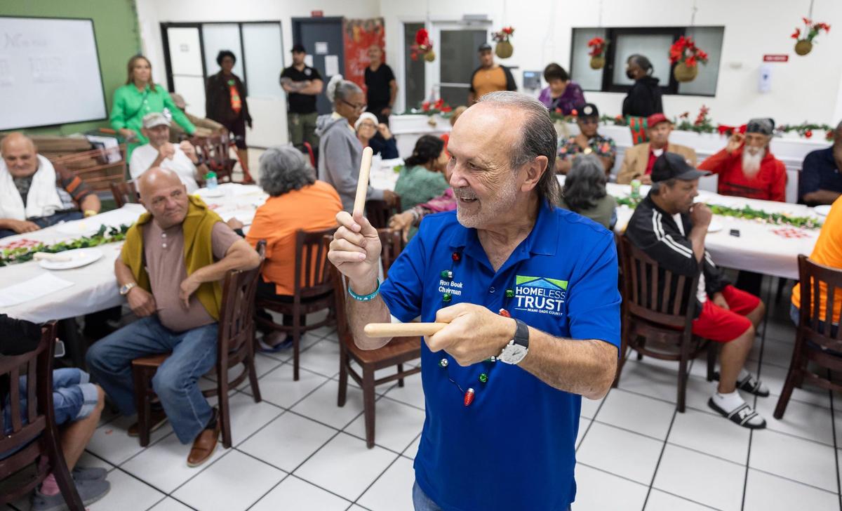 Ron Book, chairman of the Homeless Trust, plays the claves during a tree lighting event for residents at Mia Casa on Thursday, Dec. 19, 2024, in North Miami, Florida. Mia Casa, acquired by Miami-Dade County’s Homeless Trust, supports over 120 homeless seniors aged 65 and older with shelter and assistance transitioning to permanent housing.