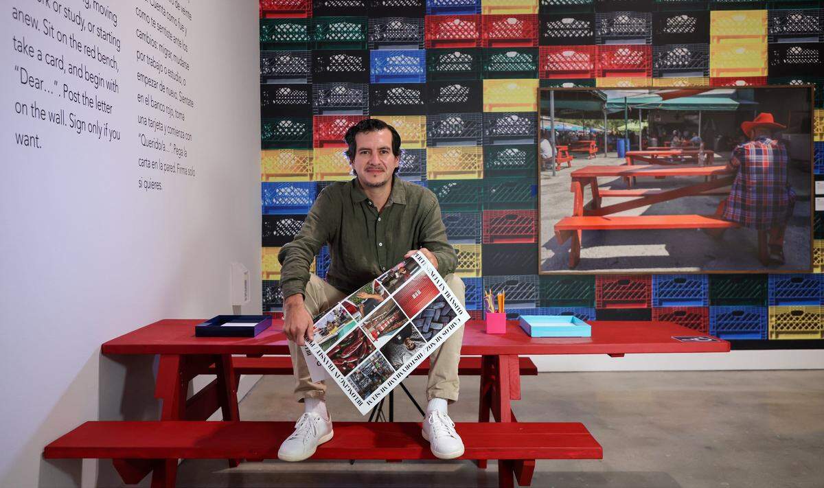 Carlos “Cali” Muñoz, a photographer awarded a 2023 grant from HistoryMiami, is documenting the Redland Market in Homestead. He is seated on a park bench at the exhibition, where attendees are invited to write their own letters. This photo exhibition explores the lives of market workers in Homestead and took place at HistoryMiami on Thursday, December 18, 2025, in Miami, Florida.