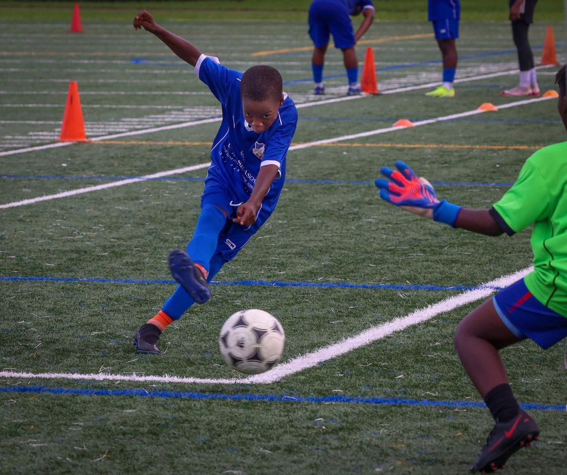 Little Haiti FC player Marcelo Saintjust, left, focuses as he scores during practice at the Little Haiti Soccer Park in Miami.