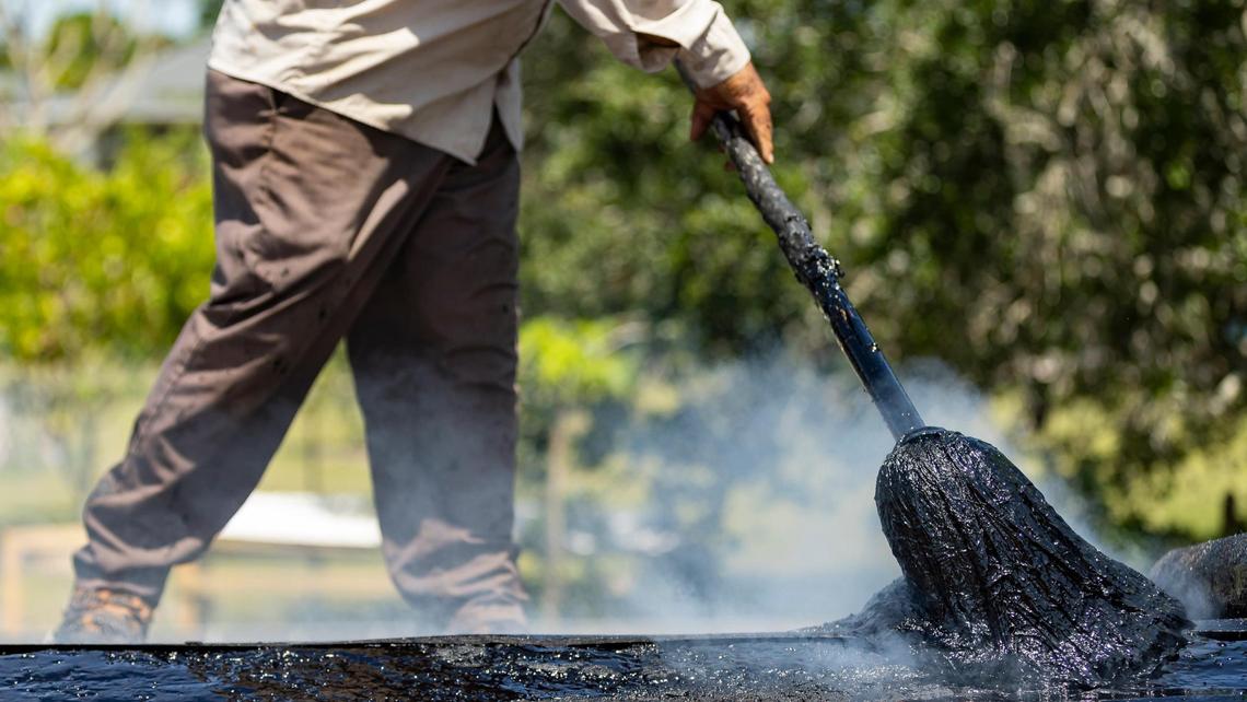 Gilberto Lujano, 49, spreads tar while working on a roof on Tuesday, May 2, 2023, in Homestead, Fla.