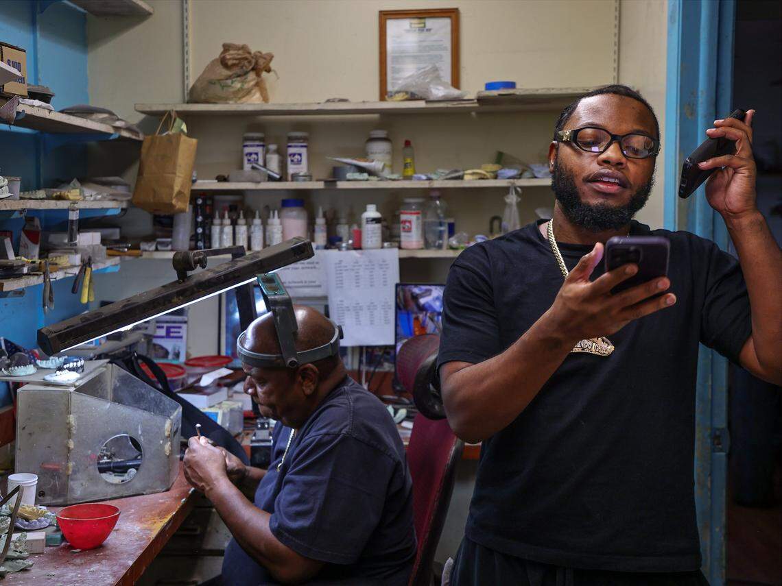 Orlando Plein, 63, works on a set of grillz with gold and diamonds as his son Phillip “Philo” Norville, 28, right, talks with customers using two phones inside Lando Golds in Miami. 