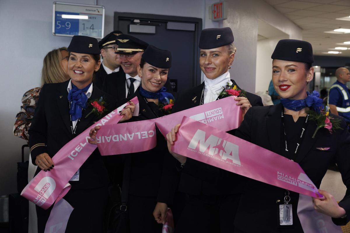 Flight attendants hold piece of the ribbon during a ceremony introducing the only direct flight between Miami and Iceland on Icelandair on Sunday, Oct. 26, 2025, at Miami International Airport in Miami, Fla.