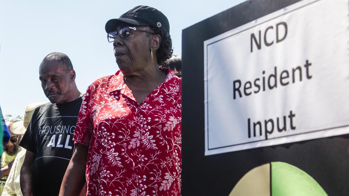 Thaddeus Scott, left, closes his eyes during prayer as community members from West Village in Coconut Grove protest zoning issues at city offices Thursday.