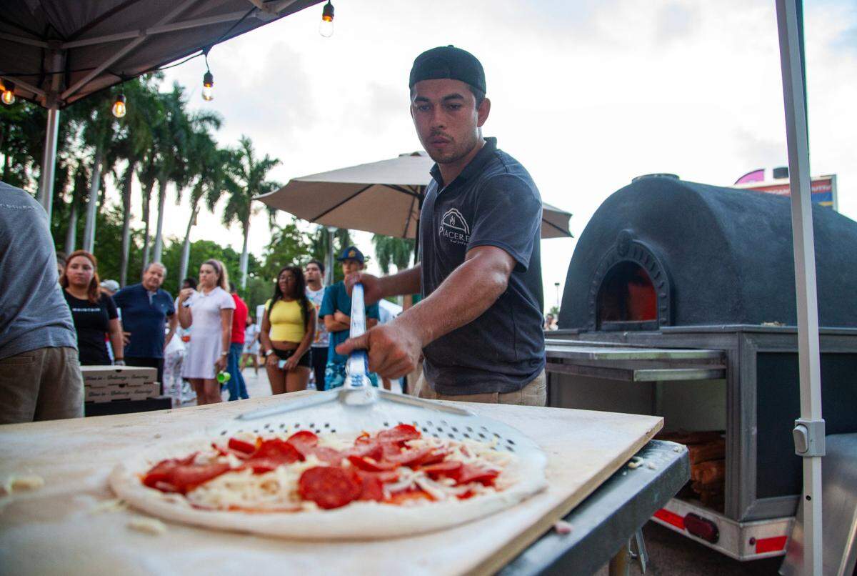 Jorge Corona, 25, of Piacere Pizza picks up a pizza before sliding it into the oven to bake during the Fourth of July Bayfront Park Celebration at Bayfront Park on Tuesday, July 4, 2023 in Miami, Fla.