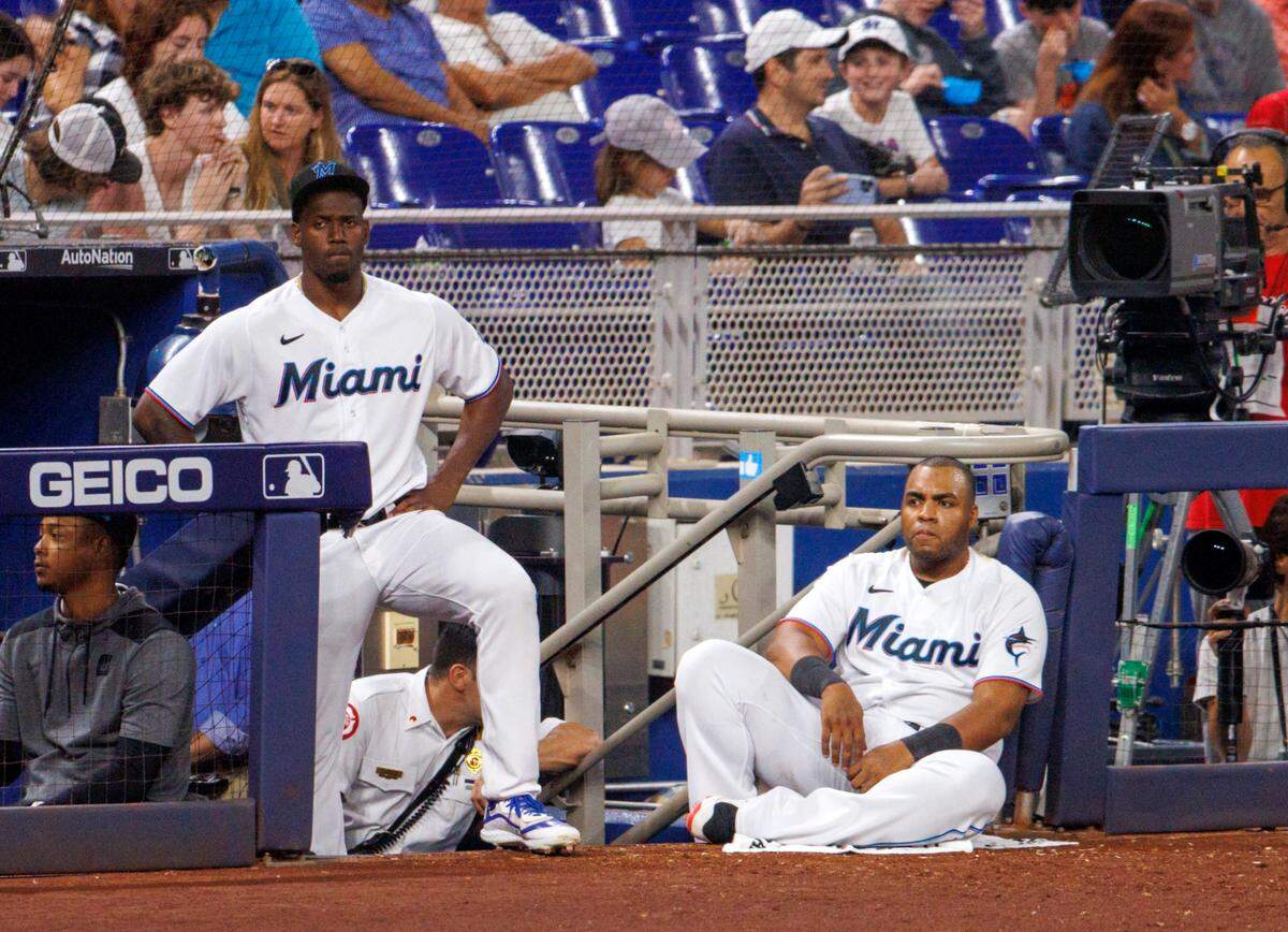 Miami Marlins players Jorge Soler (12) and Jesus Aguilar (99) look from the dugout during the eighth inning of the baseball game against the St. Louis Cardinals at LoanDepot Park on Tuesday, April 19, 2022 in Miami, Florida.