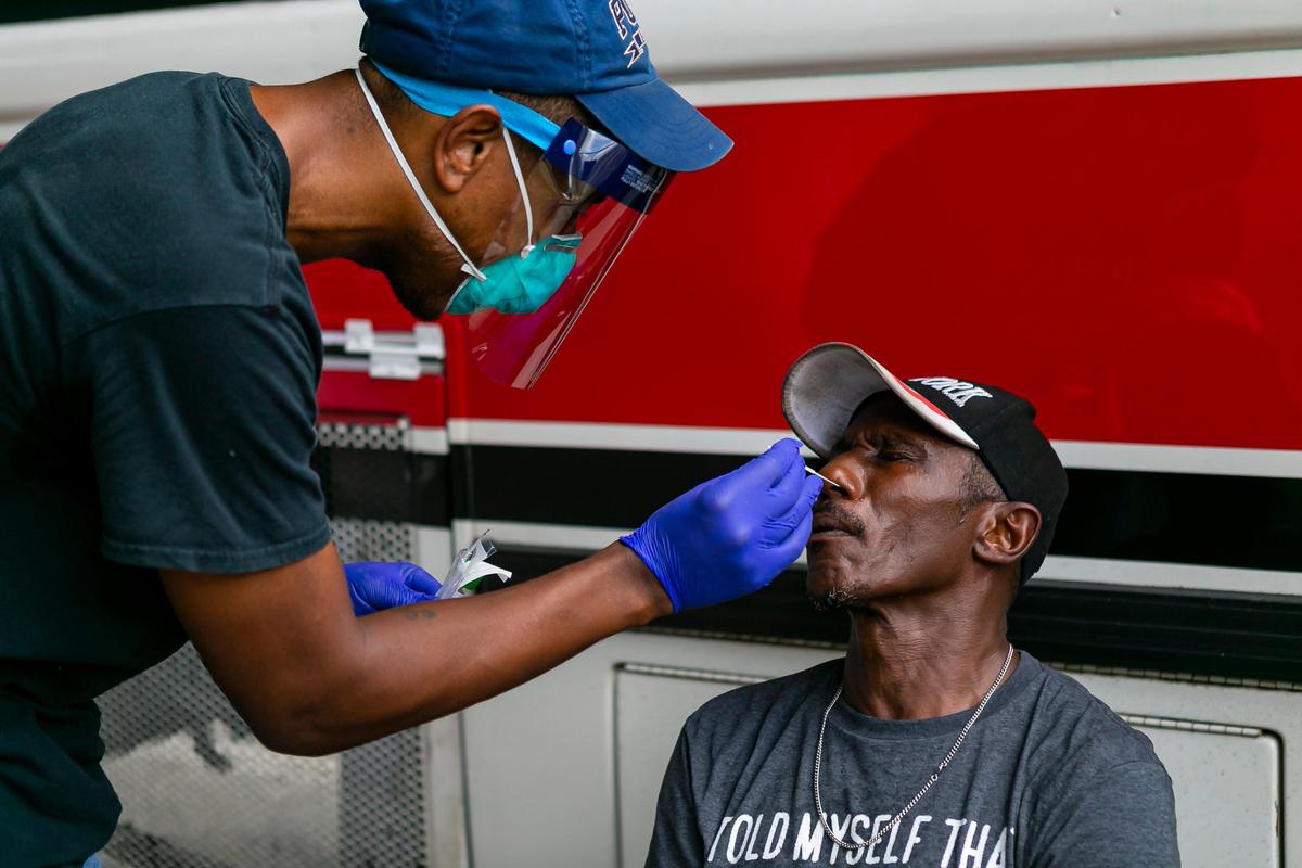 Armen Henderson, a University of Miami internist, conducts a COVID-19 test on Barry Alston in Miami’s Overtown neighborhood. Miami-Dade is renting hundreds of hotel rooms, in part to move older people experiencing homelessness out of shelters.