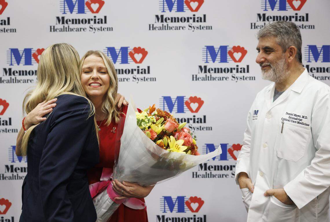 Priscilla Timmons, former ICU coma patient, center hugs Tiffany Van Slate, friend and nurse manager of intensive care unit, left, while Dr. Daniel Mayer, Critical Care Medicine Specialist and head of Timmons' care team, looks on during a gathering reuniting Timmons with her care team on Wednesday, Oct. 22, 2025, at Memorial Hospital West in Pembroke Pines, Fla. “I always tell family to talk to their loved ones in a coma,” said Mayer.