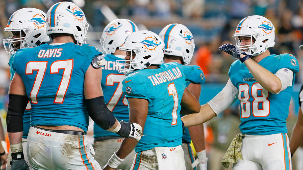 Miami Dolphins quarterback Tua Tagovailoa (1) is congratulated by teammates after scoring a touchdown against the Baltimore Ravens during the fourth quarter of an NFL football game at Hard Rock Stadium on Thursday, November 11, 2021 in Miami Gardens, Florida.