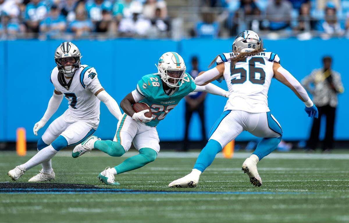 Miami Dolphins running back De’Von Achane (28) runs with the ball as Carolina Panthers safety Tre’Von Moehrig (7) and linebacker Christian Rozeboom (56) defend during the first half of an NFL football game, Sunday, Oct. 5, 2025, at Bank of America Stadium in Charlotte, N.C.