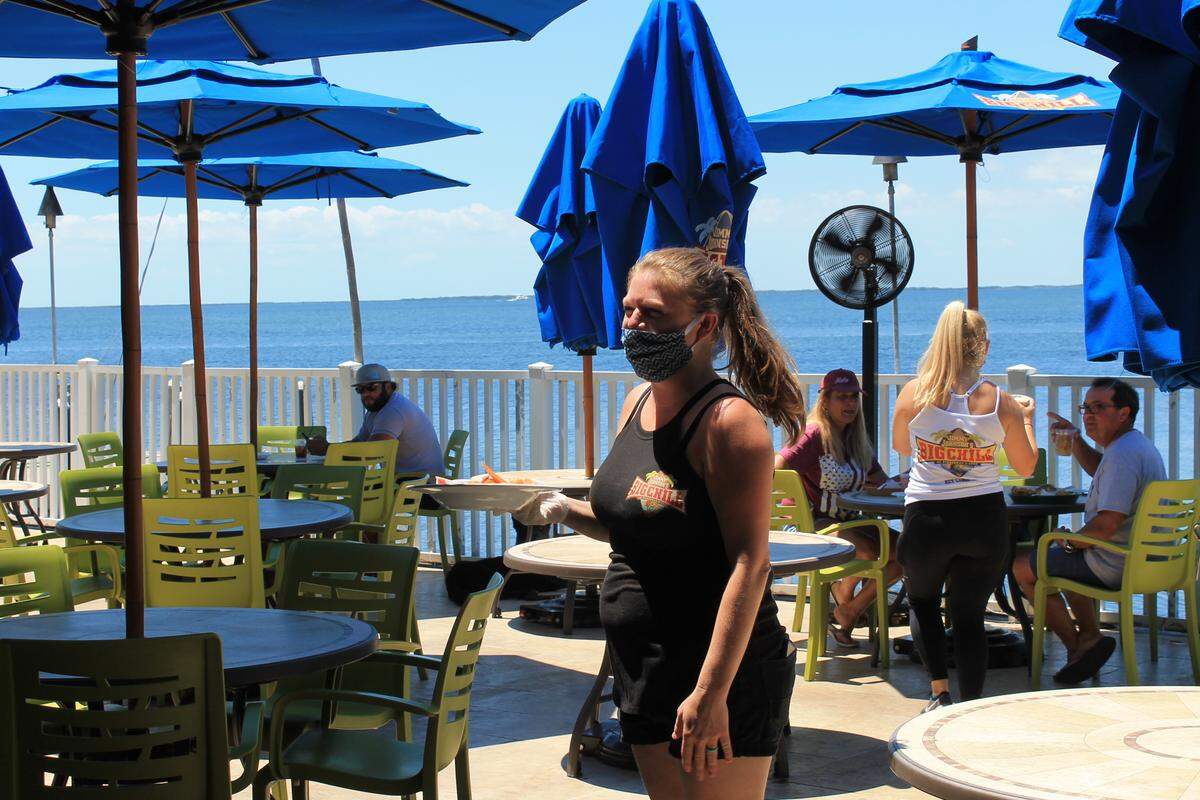 Shauna Shepard, a server at Jimmy Johnson’s Big Chill Restaurant and Grill in Key Largo, carries a plate of food Monday, May 4, 2020.