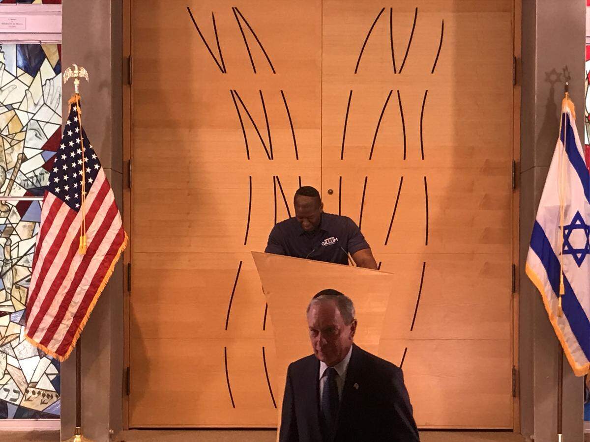 Andrew Gillum takes the lectern at Century Pines Jewish Center Sunday as former New York mayor Michael Bloomberg walks to his seat.
