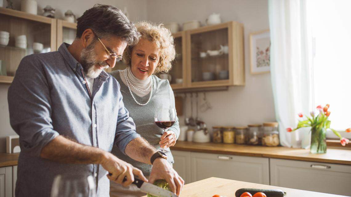 Mature couple preparing dinner for Valentines day at home, drinking vine and having fun.