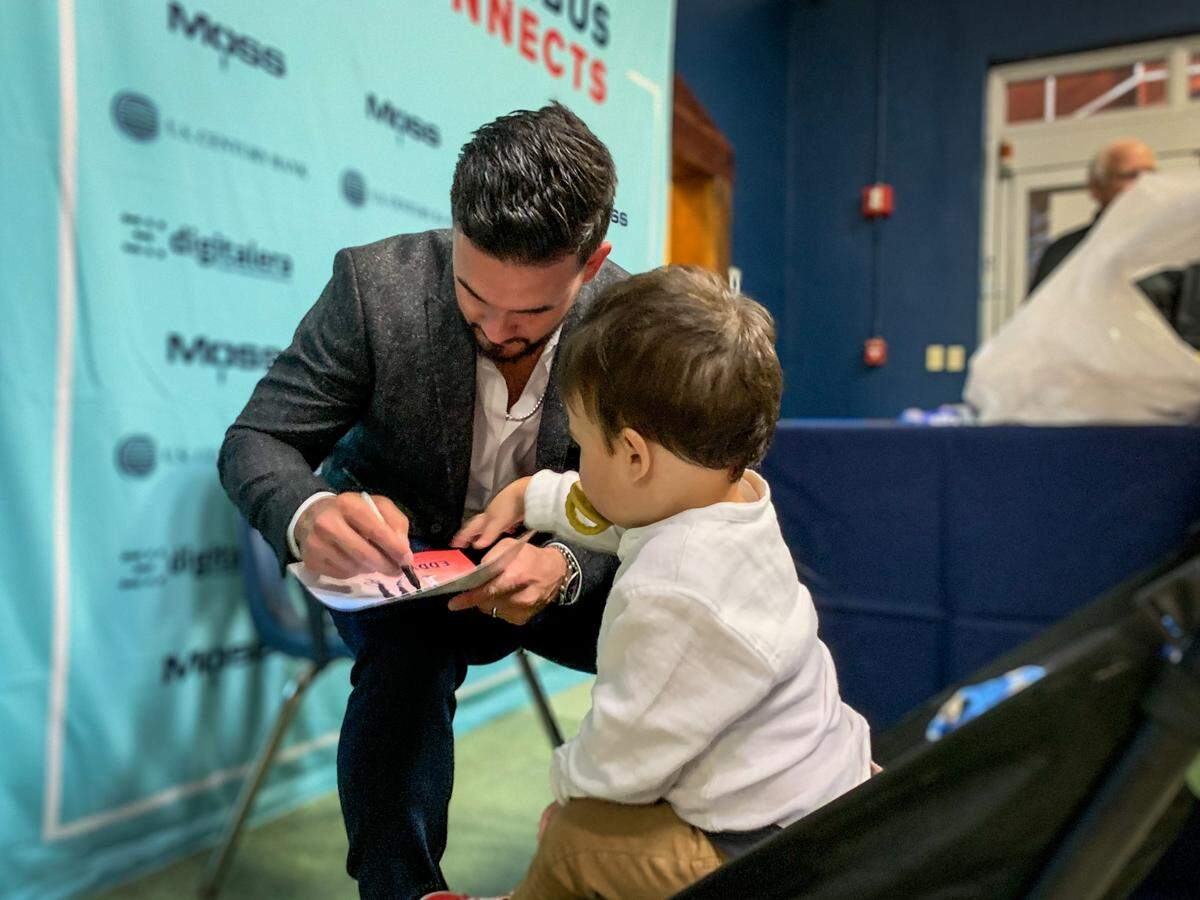 Two-time Olympic medalist Eddy Alvarez signs autographs while his son, Jett, watches after speaking at the Columbus Connects Leadership Lecture Series on Wednesday, Nov. 17, 2021.