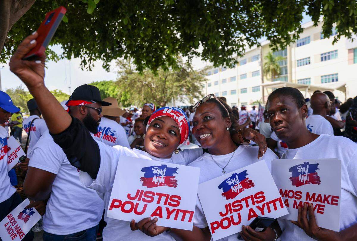 Sisters Ilene Boreal, left, Ashmine Dorval, center, and Katti Bruno, right, take a picture. About 3,500 people joined Haitians across the U.S. and the world on Sunday, July 9, 2023 to demand relief for Haiti.