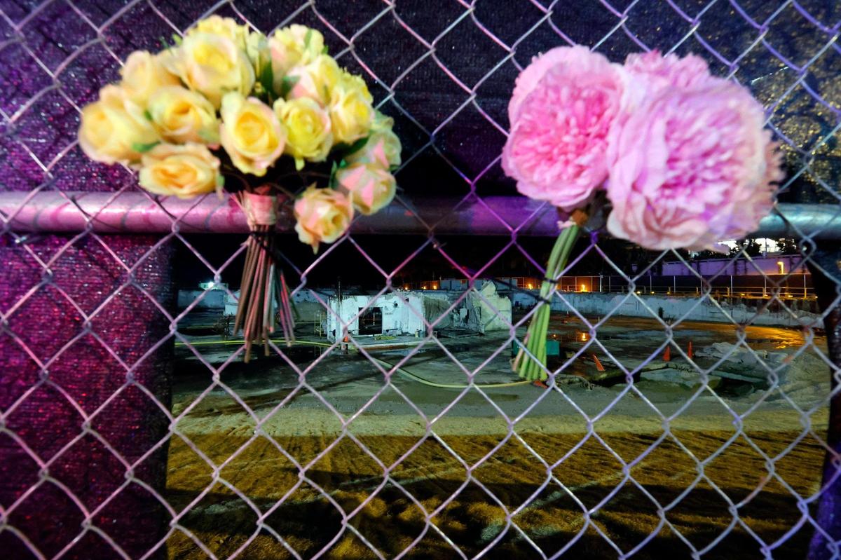Remnants of the Champlain Towers South are seen beyond the flowers placed on a fence surrounding the site on the second anniversary of the building collapse in Surfside, Florida on Saturday, June 24, 2023.