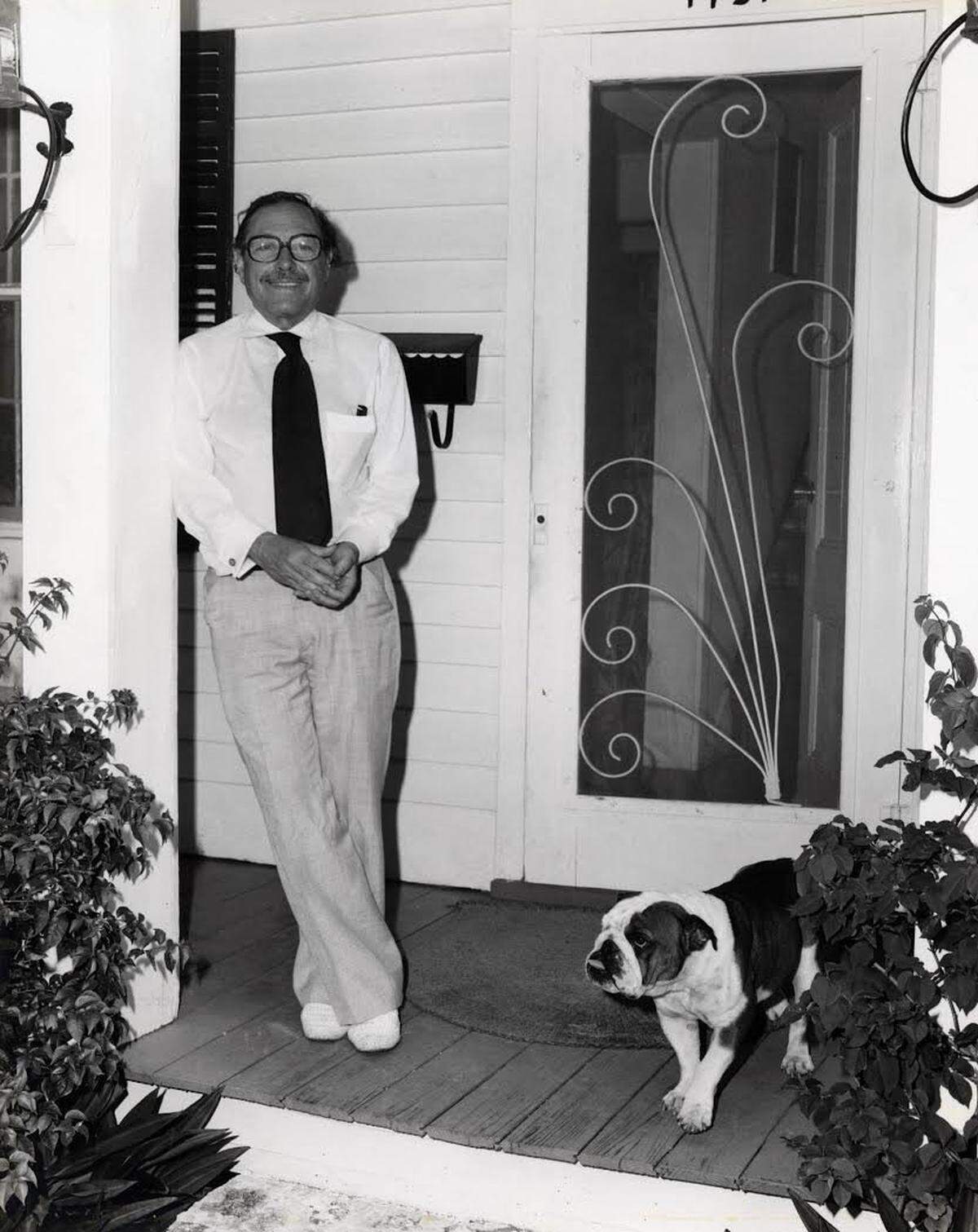Tennessee Williams stands with one of his bulldogs on the front porch of his home at 1431 Duncan St. in Key West.