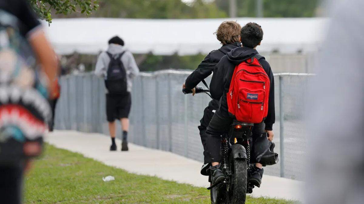 Helmetless e-bike riders enter Rickards Middle School in Oakland Park on Wednesday, April 1, 2026. E-bikes are experiencing a massive surge in popularity, nationwide and in South Florida.