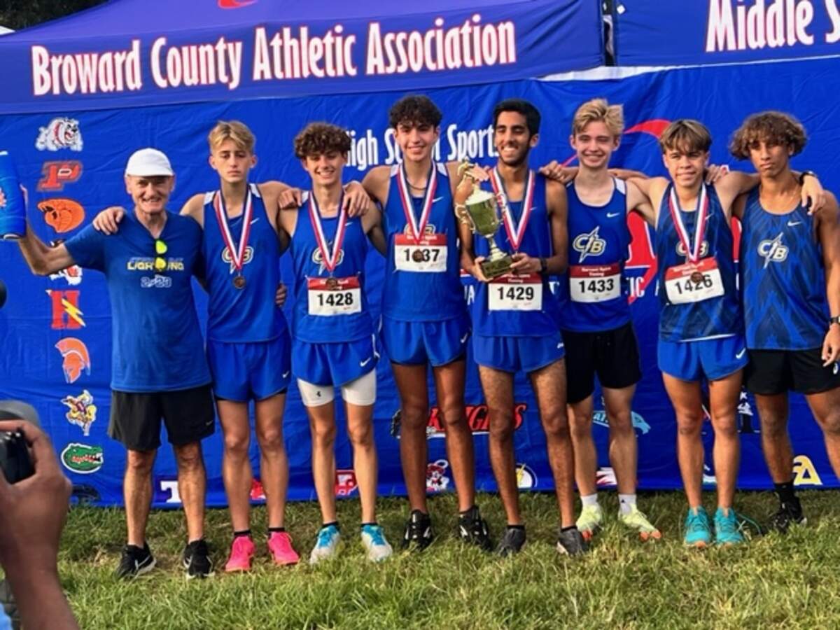 The Cypress Bay boys’ cross-country runners and coaches celebrate after winning the BCAA championship on Thursday afternoon at Markham Park in Sunrise, Fla.
