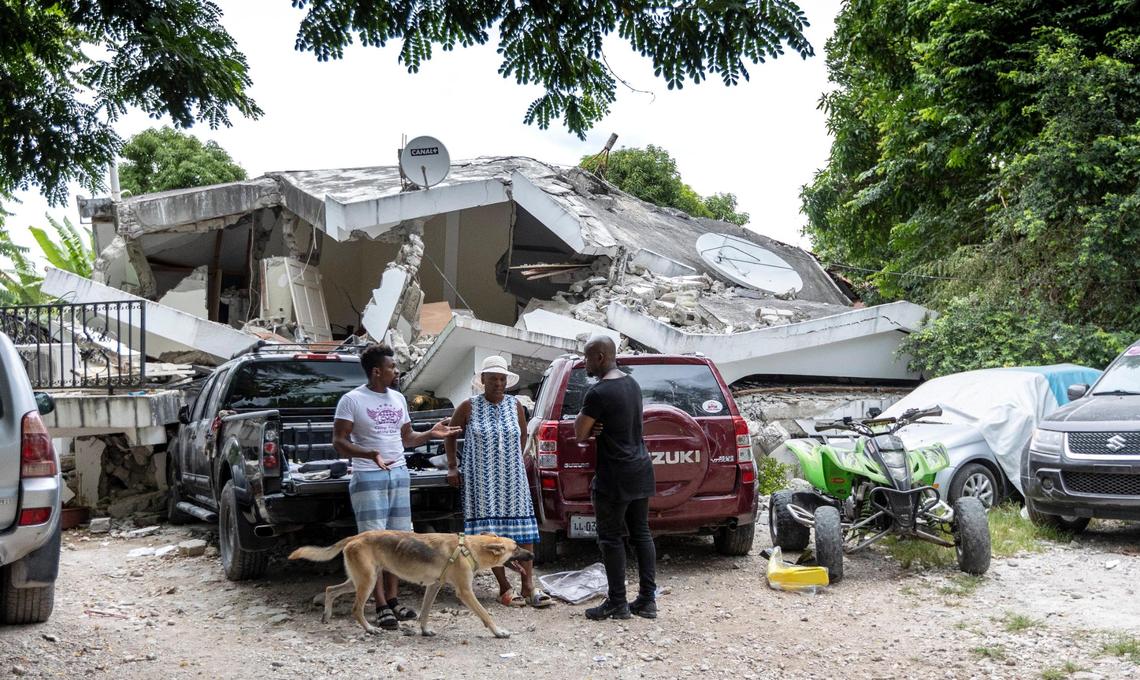 Guerda Edma Pierre-Louis, center, stands in front of what remains of her brother Roosevelt Edma’s home in Camp Perrin, Haiti, on Aug. 16, 2021. Pierre-Louis and her niece survived the Aug. 14, 2021, earthquake but her brother and his wife, Magalie, did not.