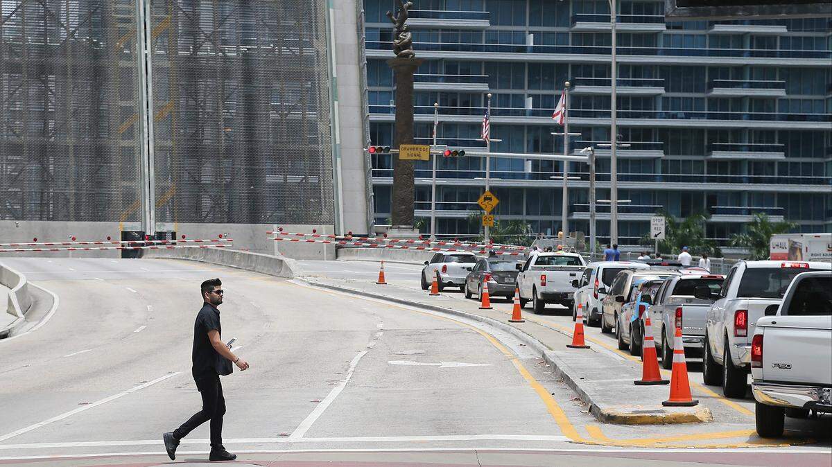 A pedestrian crosses the street as the Brickell Avenue drawbridge is raised in downtown Miami.