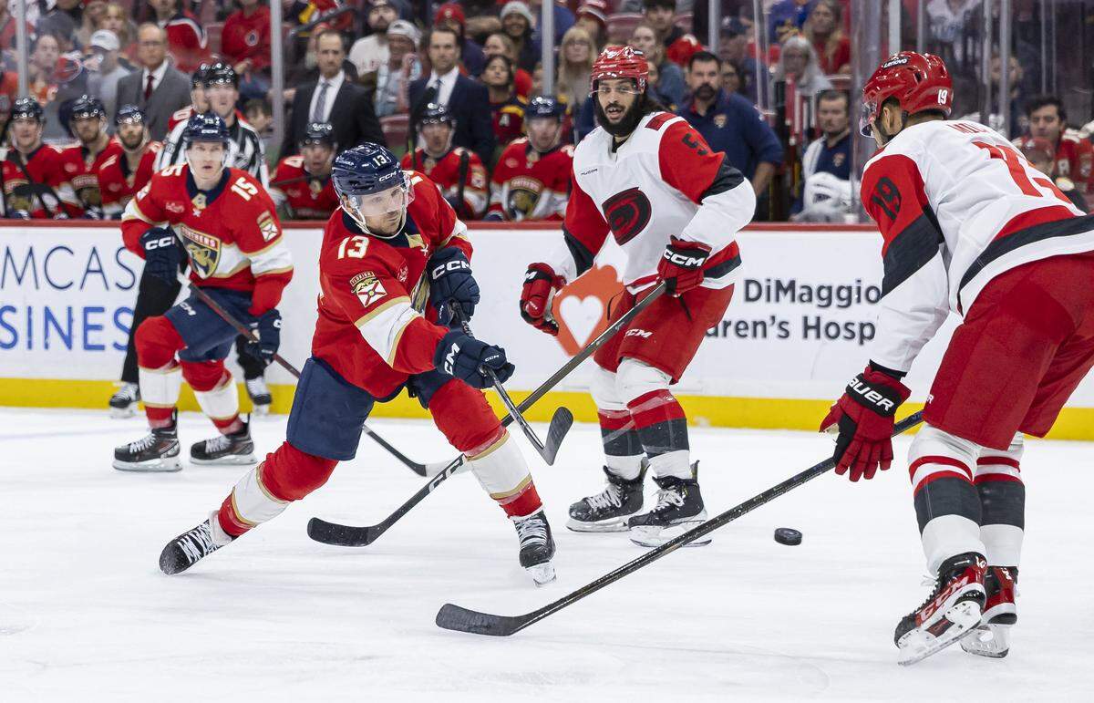 Florida Panthers center Sam Reinhart (13) shoots the puck as Carolina Hurricanes defenseman K'Andre Miller (19) defends in the second period of their NHL game at Amerant Bank Arena on Friday, Dec. 19, 2025, in Sunrise, Fla.