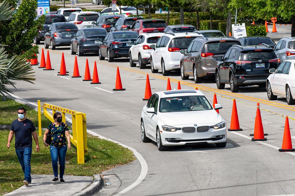 People wait in their cars as the line to get vaccinated juts out into Northwest 27th Avenue outside the FEMA-run COVID vaccination site at Miami Dade College’s North Campus in Miami, Florida, on Saturday, March 6, 2021.