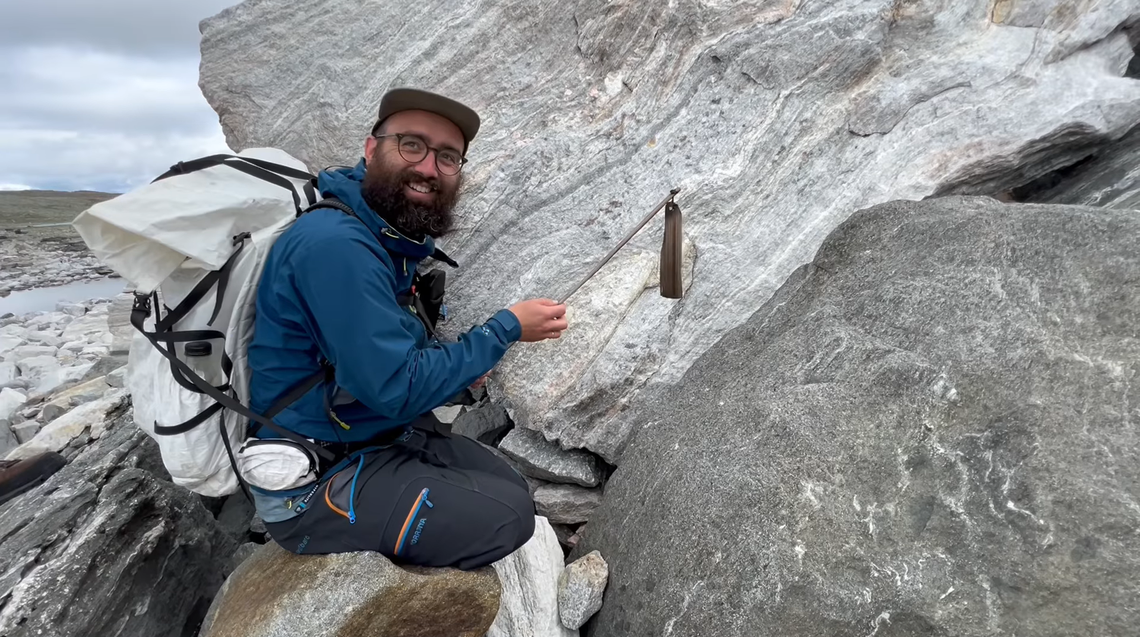 An archaeologist holds a well-preserved scaring stick found between the rocks.