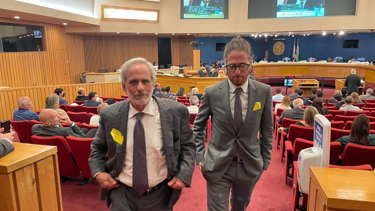 Leonard Abess Jr. (izq) y un hijo, Matthew Abess, salen de la cámara de la Comisión de Miami-Dade el 19 de mayo de 2022, después que el mayor de los Abess exhortó a la junta a rechazar la ampliación del Límite de Desarrollo Urbano para incluir 160 acres de tierras de cultivo de su propiedad. La votación final sobre el proyecto está prevista para el miércoles 1 de junio.