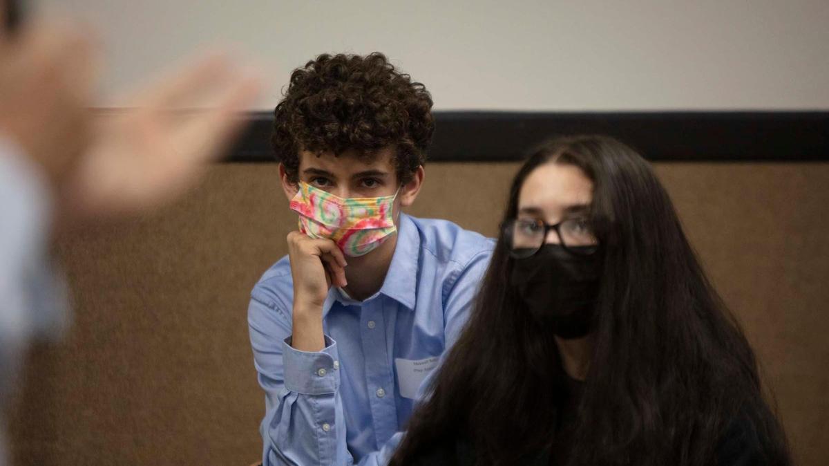 Max Sultz, 16, and Melany Alfonso, 17, listen to Allan Hall, a Holocaust survivor, talk about his experiences Thursday as part of Student Awareness Day, in which Holocaust survivors met Miami-Dade public school students to learn about the atrocities of the Holocaust. The event was at FIU’s Roz and Cal Kovens Conference Center at the school’s Biscayne Bay Campus in North Miami, March 31, 2022.