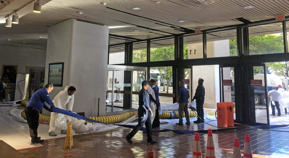 Workers clean up the Stephen P. Clark Government Center after a sewer pipe burst Tuesday.