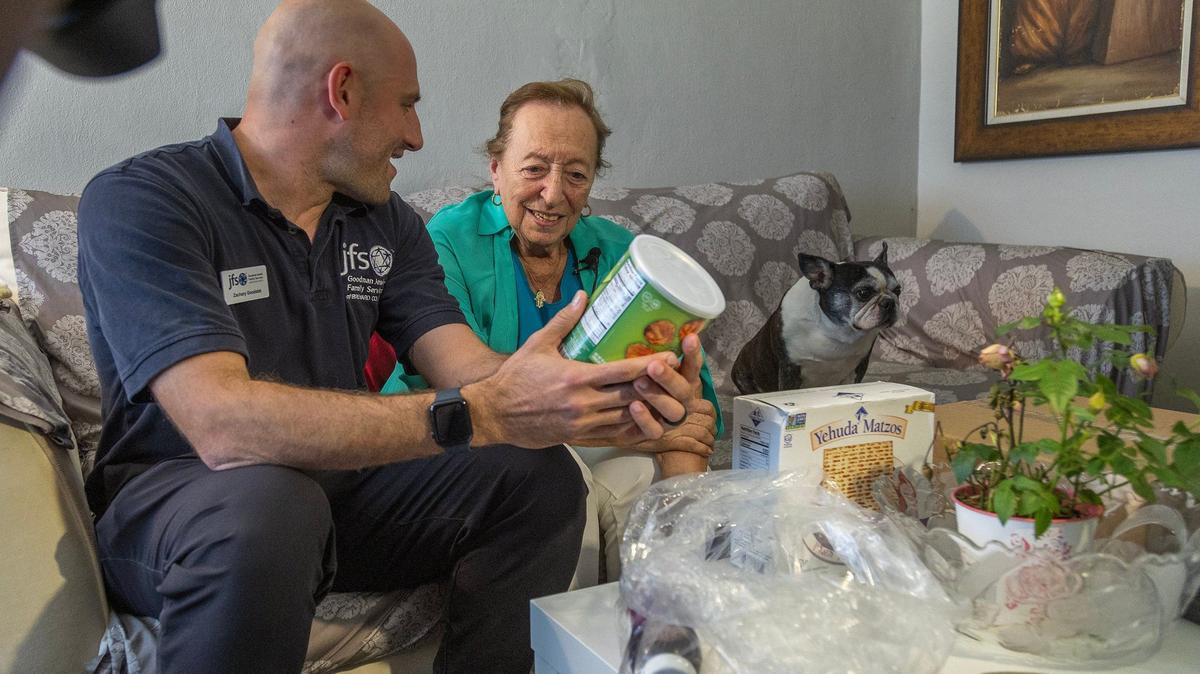 Zachary Goodstat, a care manager at JFS Broward with Holocaust survivor Agnes Berger, 88, and her dog Abigail, after delivering a Passover Seder meal to her home in Davie.