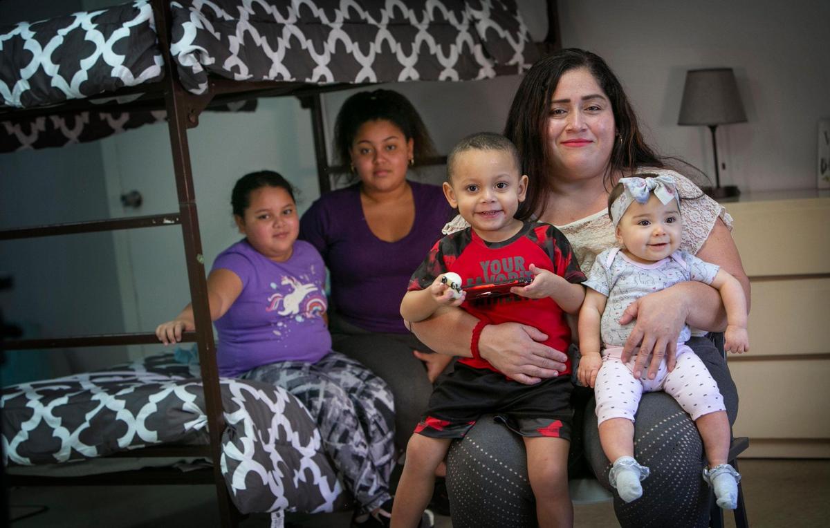 Lorena Torrente con sus cuatro hijos, desde la izquierda, Noelis de 10 años, Noelia de 15, Rafael de tres, y Melissa de nueve meses. Torrente se quedó sin hogar durante la pandemia y necesita una vivienda. La familia está siendo asistida por Miami Rescue Mission, pero espera volver a tener un lugar propio. Los niños también necesitan ropa y material escolar. La familia aparece en una de las instalaciones de alojamiento temporal de Miami Rescue Mission, donde vivieron durante un breve periodo de tiempo antes de ser colocados en otra instalación que comparten con otras dos familias.